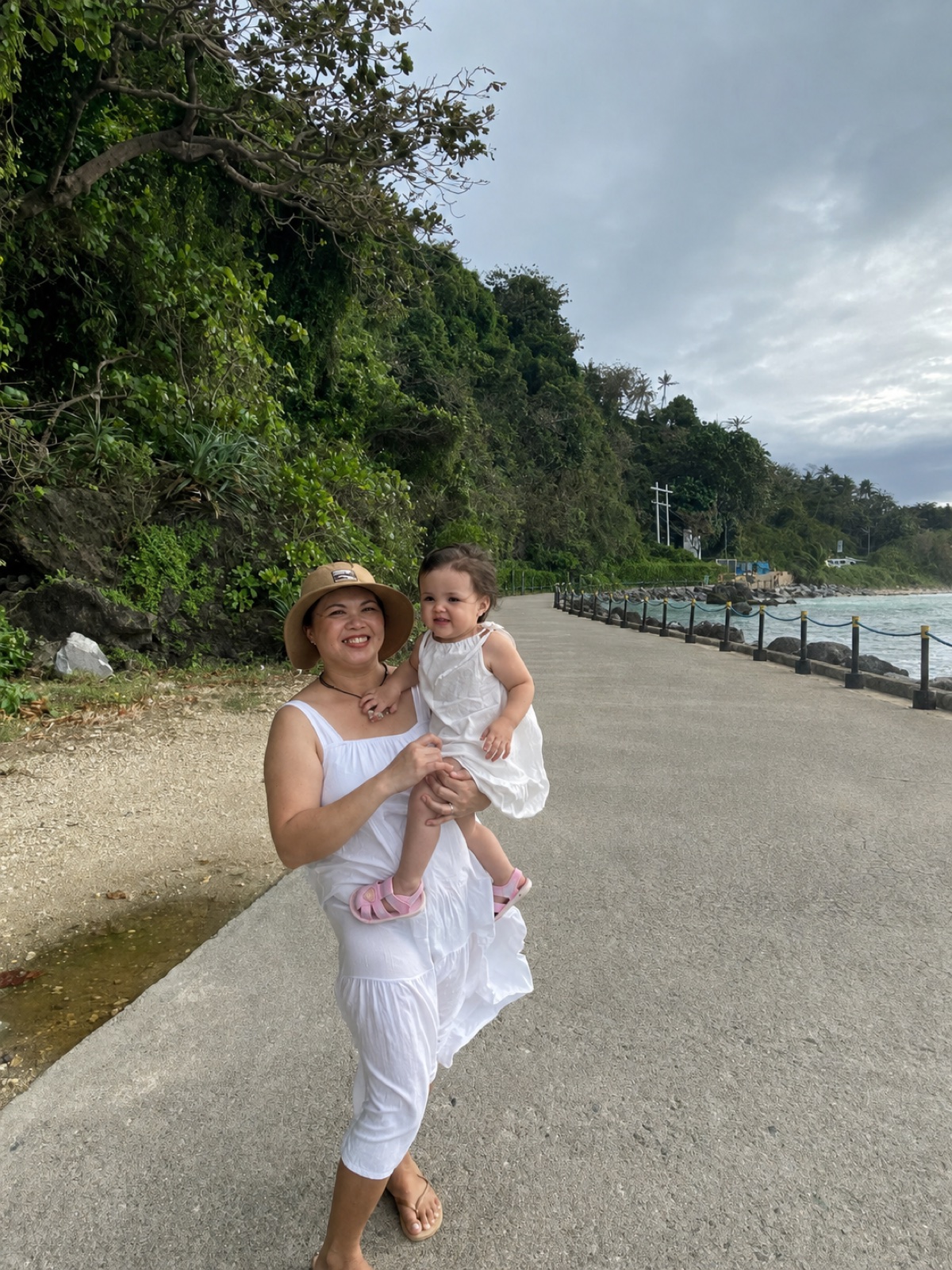 Sheryll E. smiling with her child on a coastal walk